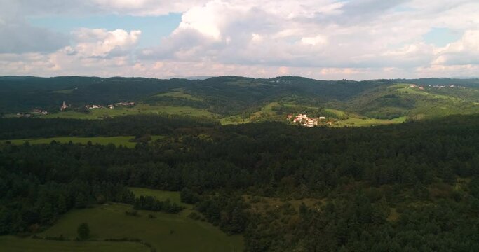 Aerial drone view over forest and fields, towards a small town in Slovenia