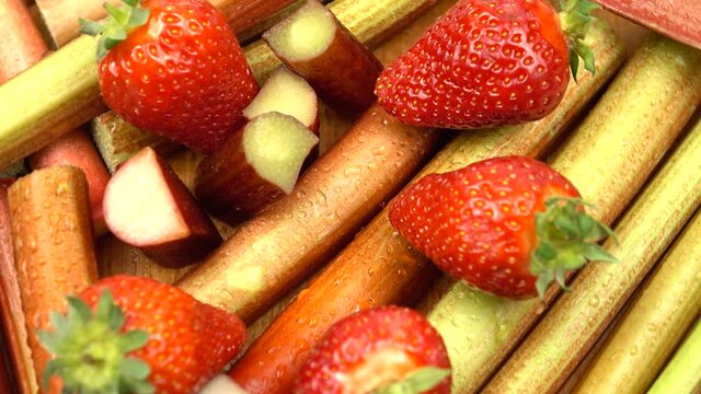 Ripe strawberries and the pieces of rhubarb stalk with drops of water on them,  products to enhance immunity, background