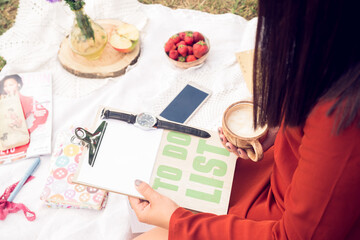 Fragmentary view of a person in a red dress holding a cup of coffee and a clip board with lettering...