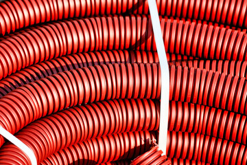 Red plastic corrugated hose for insulation and laying of wires and cable close-up.