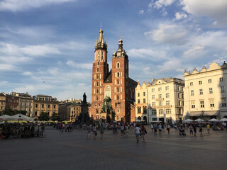 View of the St. Mary's Basilica, a Brick Gothic church adjacent to the Main Market Square in Kraków, Poland. The Adam Mickiewicz Monument can be seen in front of the church.