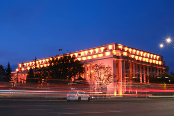 Victory Palace (Palatul Victoria) in Bucharest houses the Prime Minister of Romania and his cabinet - evening with car trails, street lights, police car.