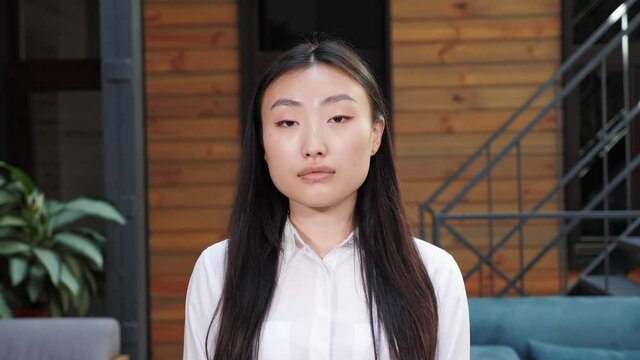 Close up view Face of beautiful soft chinese business woman with natural make-up looking at camera. Portrait of young asian pretty brunette girl standing in meeting room. Ethnicity. People. Beauty.