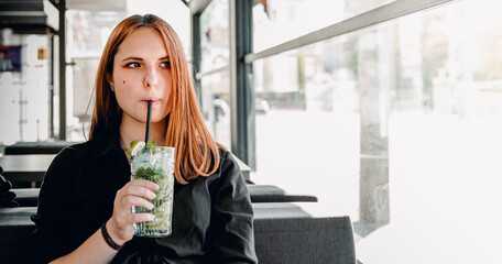 young teenager girl holding glass with a lemonade cocktail and drink in cafe