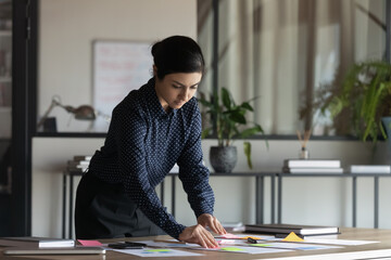 Focused young Indian businesswoman prepare company financial startup project in office. Confident...