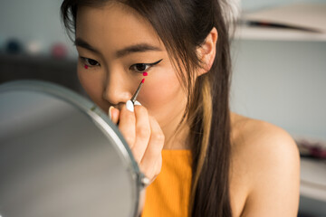 Woman with brunette hair holding brush with shadows and mirror while making make up