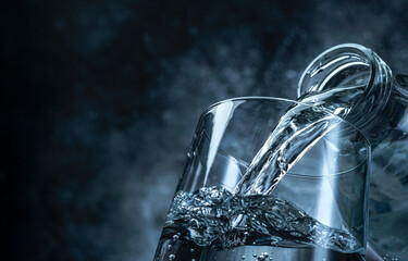 Pouring water from bottle into glass on black background
