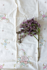 sprig of lilac bud-blossoms on vintage embroidered cotton doily or table runner - photographed from above in flat lay style, with space for text