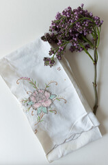 sprig of lilac bud-blossoms on vintage embroidered cotton doily or table runner - photographed from...