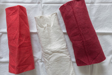 red and white felt fabric rolled on white cotton material - photographed from above with ambient light 