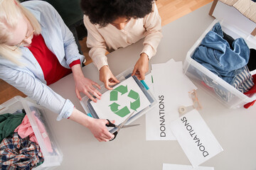 Motivated colleagues sticks a recycling symbol on a plastic box with a sorting clothes