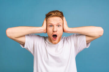 OMG! It's incredible! Portrait of amazed shocked young man looking at camera while standing isolated over blue background. Close up portrait of bearded man keeping his mouth open.