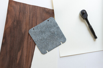 galvanized metal plate with holes, sprocket wrench, paper, and wood veneer  - photographed from above with ambient light - obrazy, fototapety, plakaty
