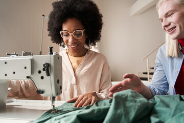 Multiracial seamstress using sewing machine in work while re sewing clothes