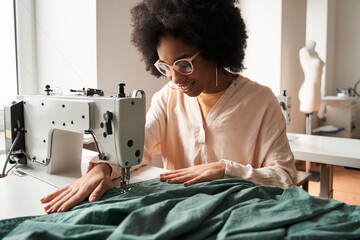 Woman inserting the fabric under the needle at the sewing machine