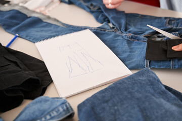 Sketch laying at the table around the different jeans being ready for the re sewing