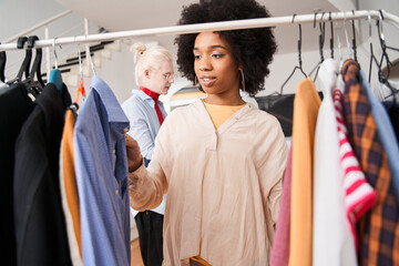 Fototapeta premium Woman looking through the hangers with clothes ready for alteration