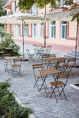 Fototapeta na wymiar table and chairs on the terrace empty street cafe with garden