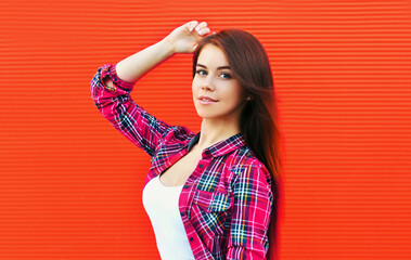 Portrait of beautiful young brunette woman in a city on red background