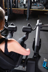 back view of amputee woman working out on leg extension exercise machine