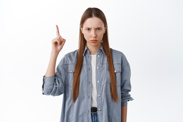 Angry sulking girl frowning, pointing up at unfair thing, being jealous or upset, complaining,...