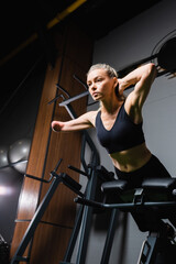 Fototapeta na wymiar low angle view of amputee sportswoman doing abs exercise on fitness machine