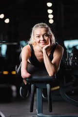 happy amputee woman lying on exercise machine and smiling at camera