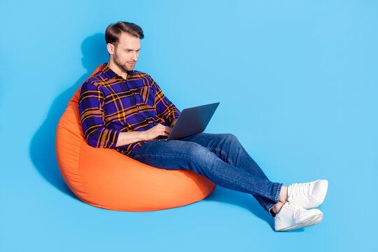 Full body photo of serious focused young man sit bean bag write laptop job  isolated on pastel blue color background Photos | Adobe Stock