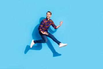 Fototapeta na wymiar Full body photo of happy cheerful funny young man play imagine guitar jump up air isolated on blue color background