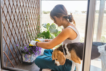 Young woman gardening on her balcony with her dog