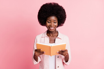 Portrait of pretty focused cheerful wavy-haired girl holding in hands reading diary isolated over...