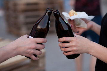 beer bottles raised for a toast. Hands of women clinking bottles.