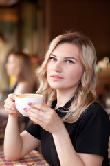 Young woman drinking a coffee in a cafe terrace with friends