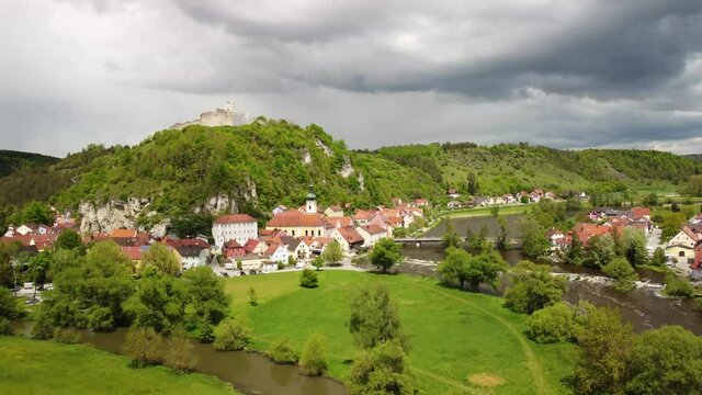 Drone rising high above the town and castle ruin of Kallm&uuml;nz in Bavaria, Germany on sunny day with dramatic clouds