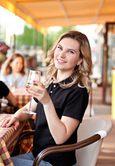 Young woman drinking a white wine in a cafe terrace with friends
