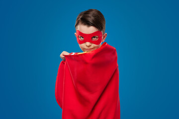 Confident superhero boy in red cape and mask