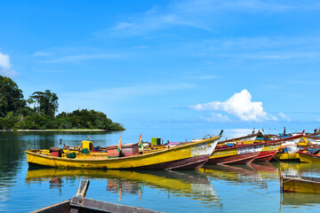 Wide shot of colorful fishing boats docked at the river mouth. Punts parked at the riverside.