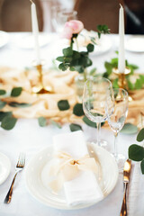 Festive table setting in gentle pastel colors. Plate and glasses close up. Gala dinner in honor of...