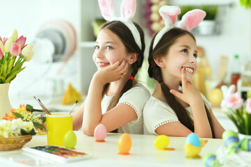 Cute twins wearing rabbit ears decorating  Easter eggs