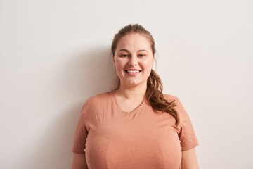 Fototapeta premium Woman in casual clothes is standing indoors and looking at camera with wide smile