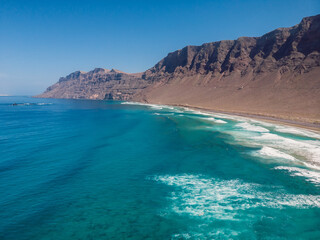 Aerial view of Famara beach with scenic landscape, blue ocean and mountains in Lanzarote