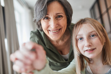 Woman looking at the masterpiece while helping to drawing to her granddaughter