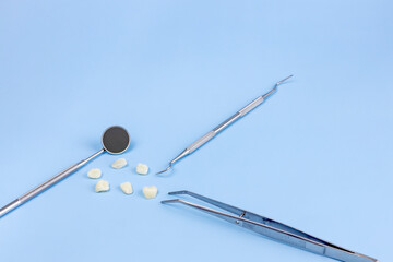 models of teeth, dental mirror, tweezers and dental probe on a blue background. the concept of proper dental care