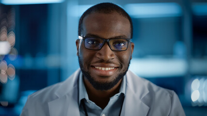 Obraz premium Handsome Black Man Wearing Glasses Smiling Charmingly Looking at Camera. Young Intelligent Male Engineer or Scientist Working in Laboratory. Technological Bokeh Blue Background. Close-up Shot
