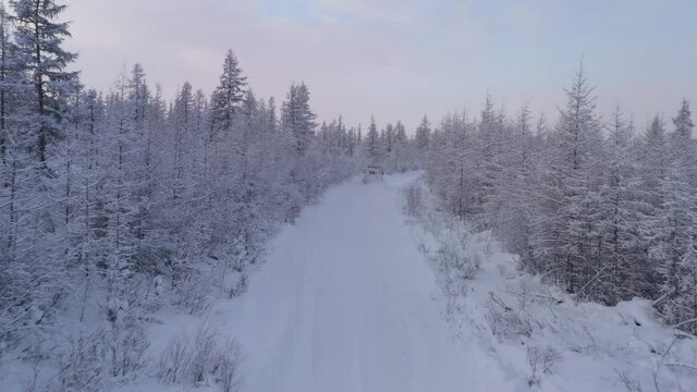 The six-wheel Trekol all-terrain vehicle rides through the snow-covered tundra in the sunset light
