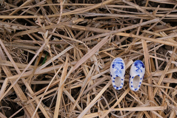 A small pair of ceramic klompen (clogs) on the straw background. Copy space.