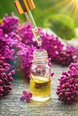 Lilac essential oil in a small bottle. Selective focus.