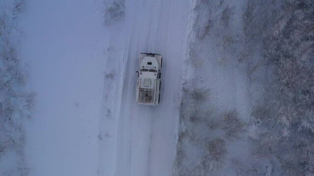 The six-wheel Trekol all-terrain vehicle rides through the snow-covered tundra in the sunset light
