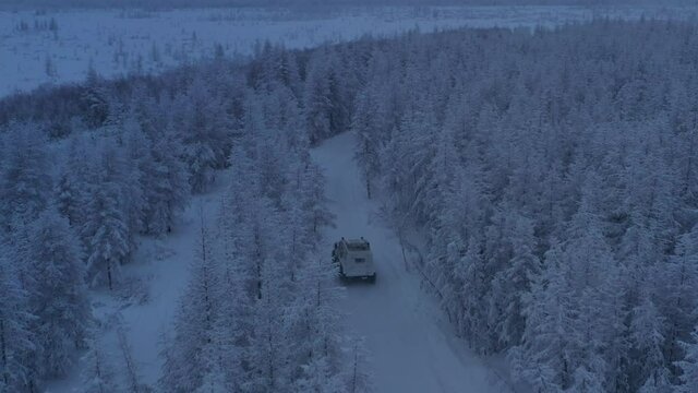 The six-wheel Trekol all-terrain vehicle rides through the snow-covered tundra in the sunset light
