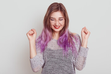 Happy excited woman celebrating victory clenching fists and smiling toothily, being glad to achieve...